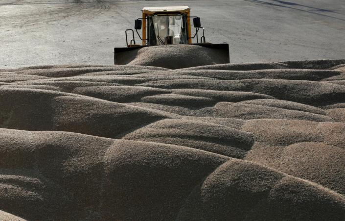 FILE PHOTO: A driver operates a tractor to pile wheat grains at the drying house of the Solgonskoye farming company near Talniki